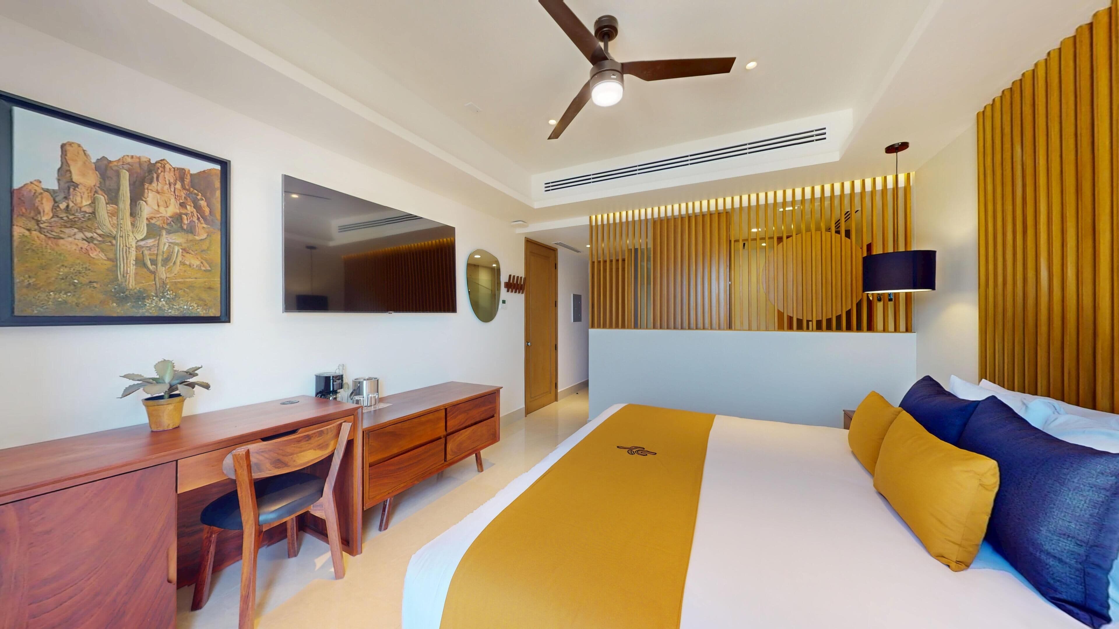Una habitación de hotel moderna con cama, escritorio, silla y un cuadro grande en la pared.