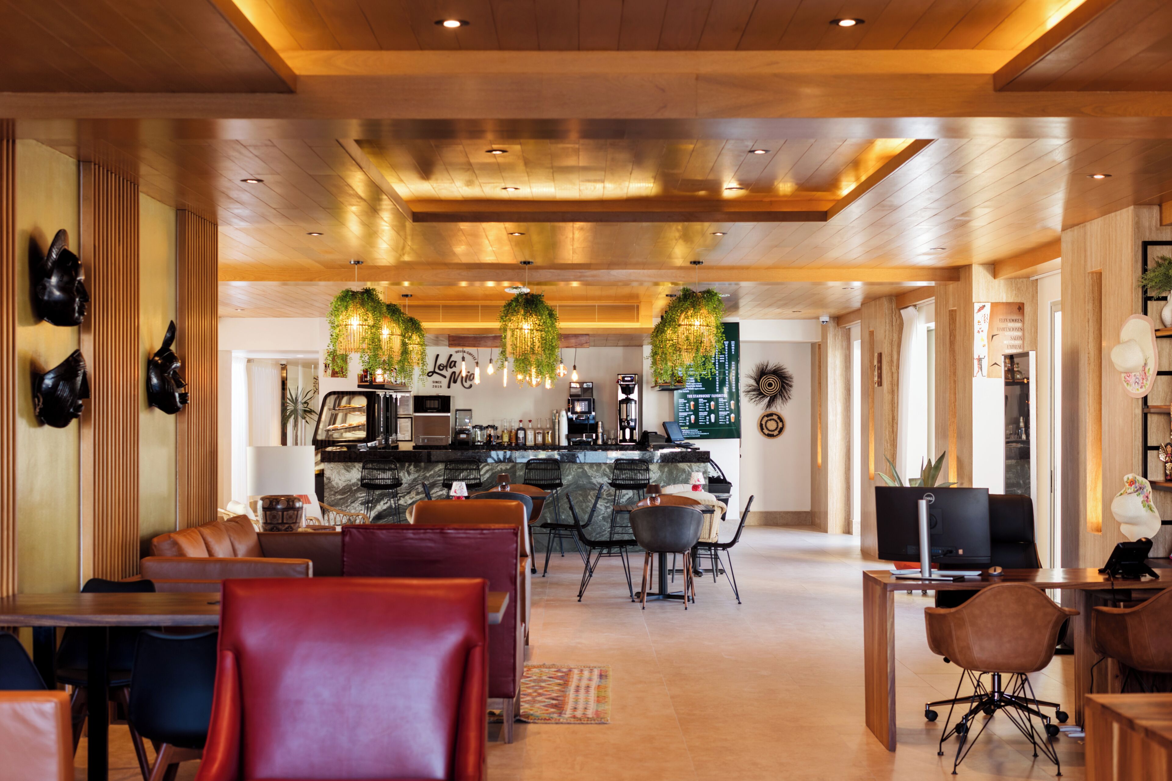 Een moderne hotellobby met een bar, zithoekjes en een houten plafond.