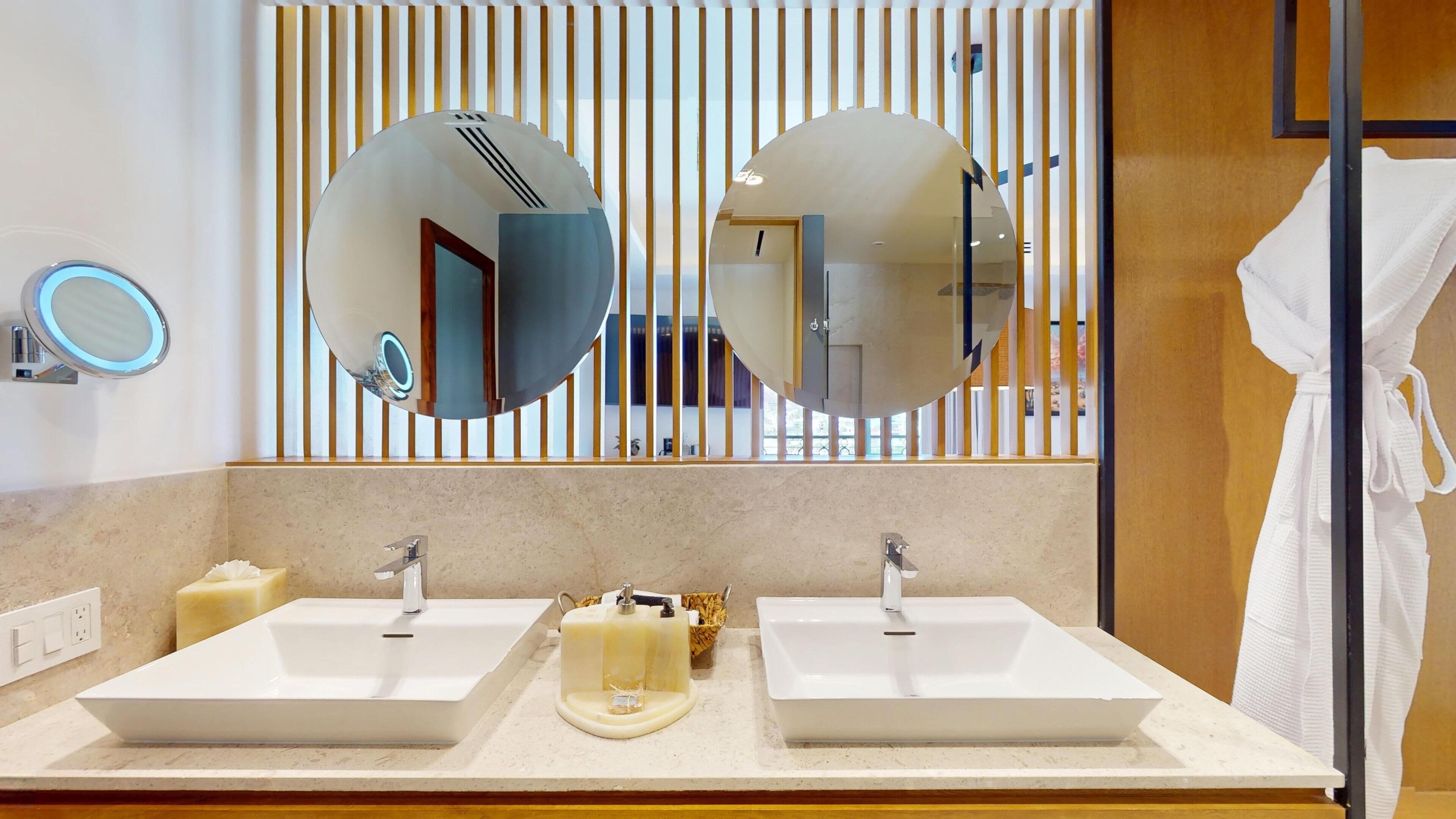 Un baño moderno con dos lavamanos, un espejo y un perchero para toallas.