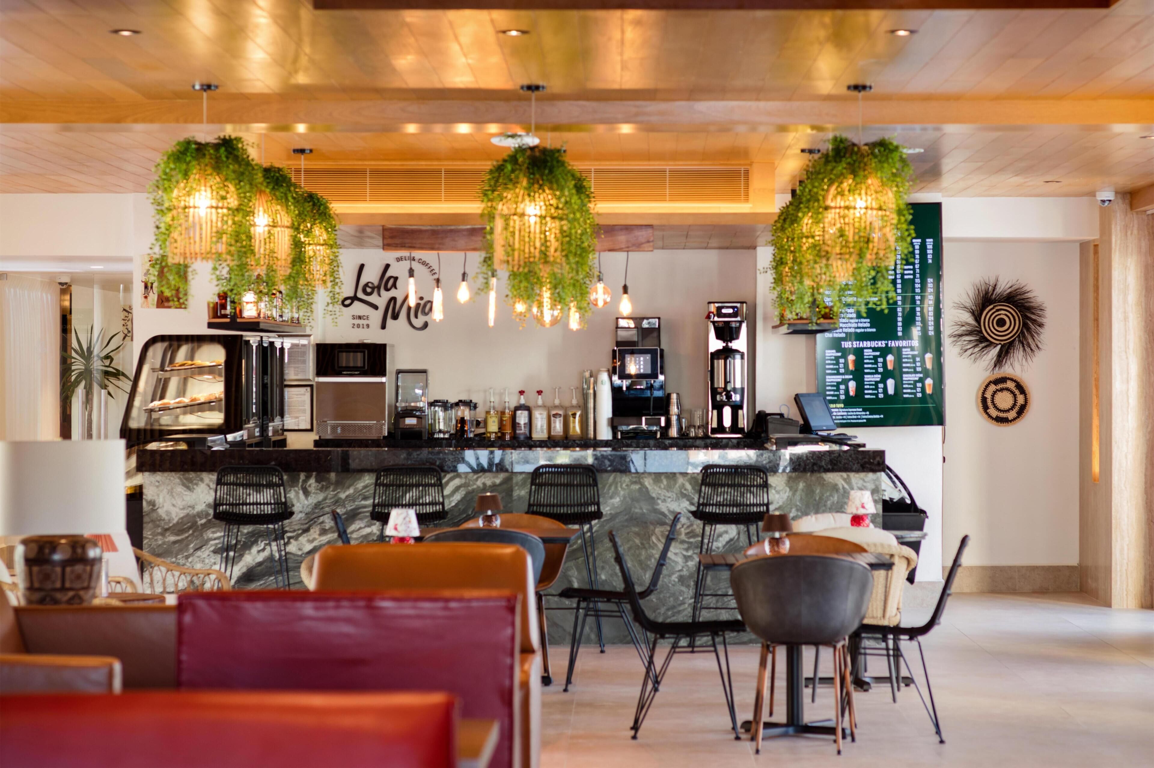 Un espace bar avec un comptoir, des sièges et des plantes suspendues.