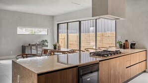 A modern kitchen with a central island, wooden cabinets, and a built-in dishwasher. - The Brown Oak: Nature & Splendor (Conroe)
