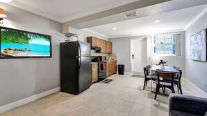 Une cuisine moderne avec un réfrigérateur noir, des meubles de rangement en bois et un coin repas comprenant une table et des chaises.
