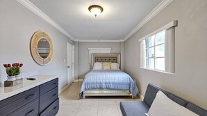 Une chambre à coucher comprenant un lit, une commode, une coiffeuse, un miroir et une fenêtre.