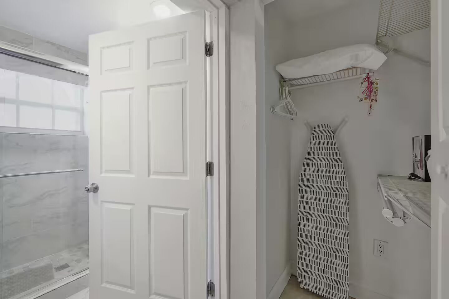 Une salle de bain avec une porte blanche, un espace douche, un porte-serviettes et une serviette suspendue.