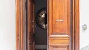 A wooden door with a handle, a doormat, and a wall-mounted mirror.