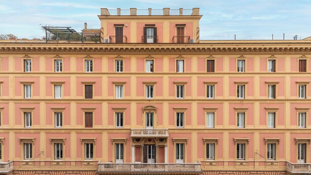 A multi-story building with a symmetrical facade, featuring evenly spaced windows and a central entrance with an archway.