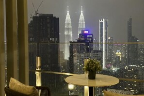 A room with a view of a city skyline, a round table with a vase, and a chair. - Agile Residence Bukit Bintang by Heystay Management (Kuala Lumpur)