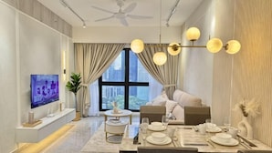 A modern living room with a dining area, a flat-screen TV, a ceiling fan, and a large window with curtains.