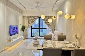 A modern living room with a dining area, a flat-screen TV, a ceiling fan, and a large window with curtains.