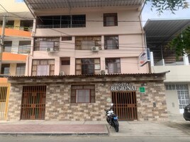 Un edificio con un letrero que dice "HOSTAL REGIONAL" y una motocicleta estacionada adelante.