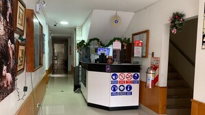 A reception area with a counter, a fire extinguisher, and a sign with health and safety instructions. - hostal regional (Piura)