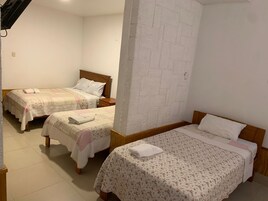 Habitación de hotel con dos camas individuales, cabecero de madera, pared decorativa con diseño de ladrillos y suelo de baldosas.