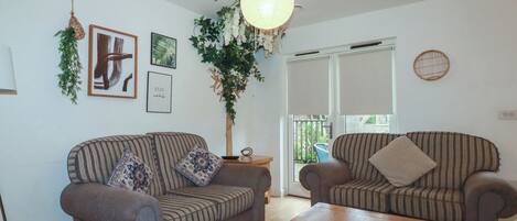 A living room with two striped sofas, a wooden coffee table, and a hanging light fixture.