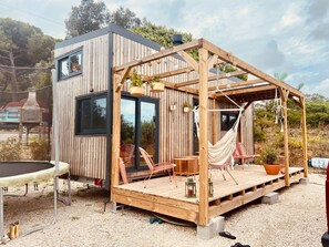 A wooden cabin with a deck, outdoor seating, and a hammock.