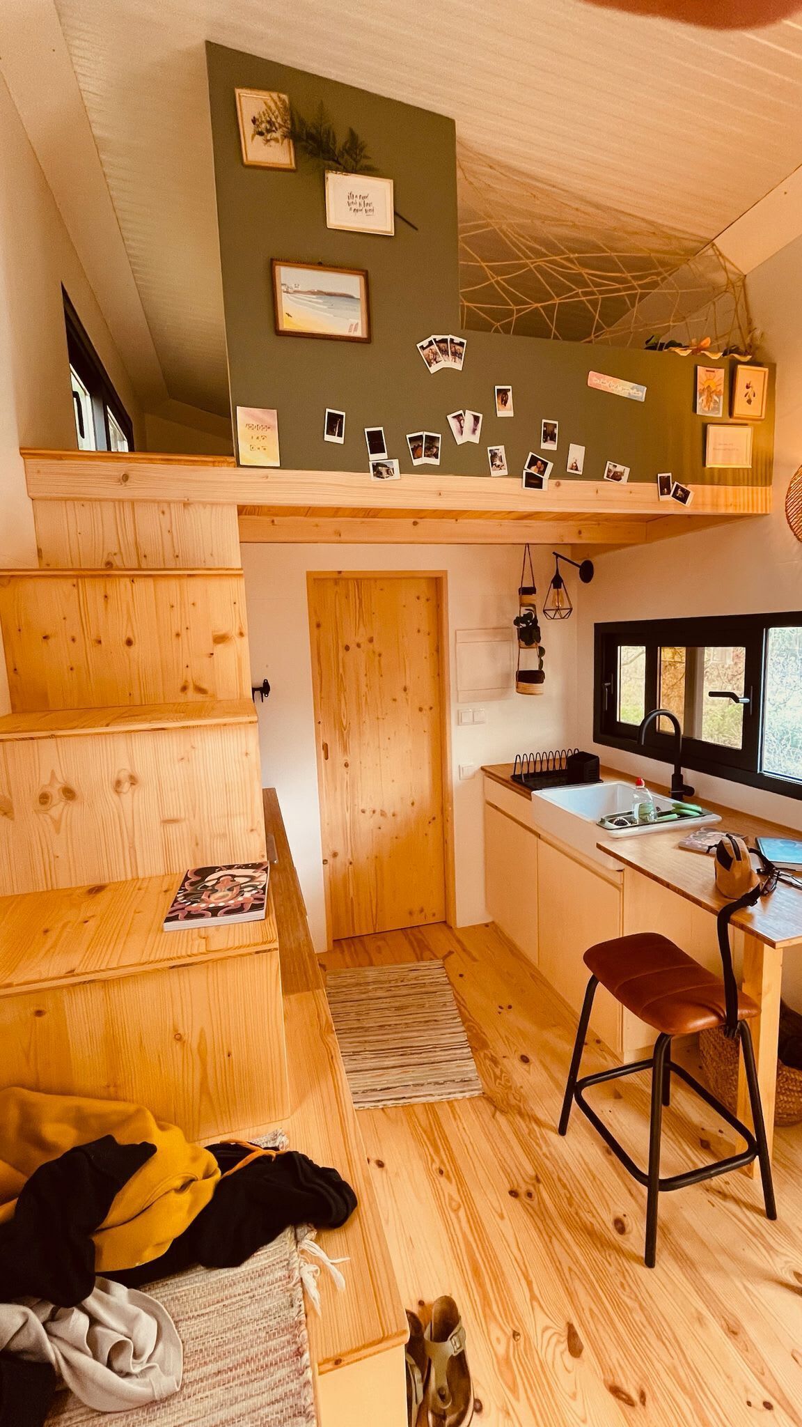 A compact kitchen with a wooden countertop, a bar stool, and a window above the sink.