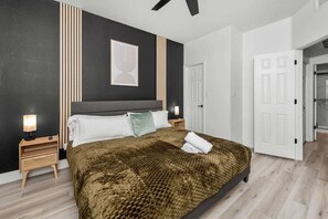 A modern bedroom with a large bed, a dark accent wall, and a framed artwork above the bed. - Sleek 2BR-Pool, BBQ, Prkng, Yoga Rm, Gym, Cabanas (Scottsdale)