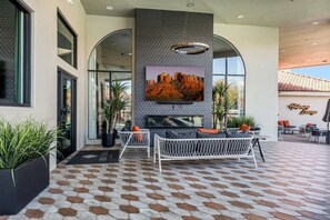 Un espacio al aire libre moderno con una televisión grande de pared, plantas en macetas y un suelo estampado.
