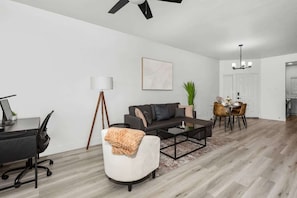 A modern living room with a sofa, coffee table, and dining area.