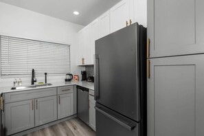 A modern kitchen with grey cabinets, a black refrigerator, and a sink with a faucet.