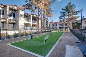 Een wooncomplex met meerdere appartementencomplexen, een omheinde binnenplaats met een gazon en een bank.