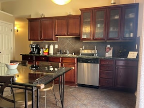 A kitchen with wooden cabinets, a dishwasher, a coffee maker, and a toaster. - Comfy 3-bedroom Home with Amenities for Long Term Stays (El Paso)