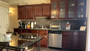 A kitchen with wooden cabinets, a dishwasher, a coffee maker, and a dining table with chairs.