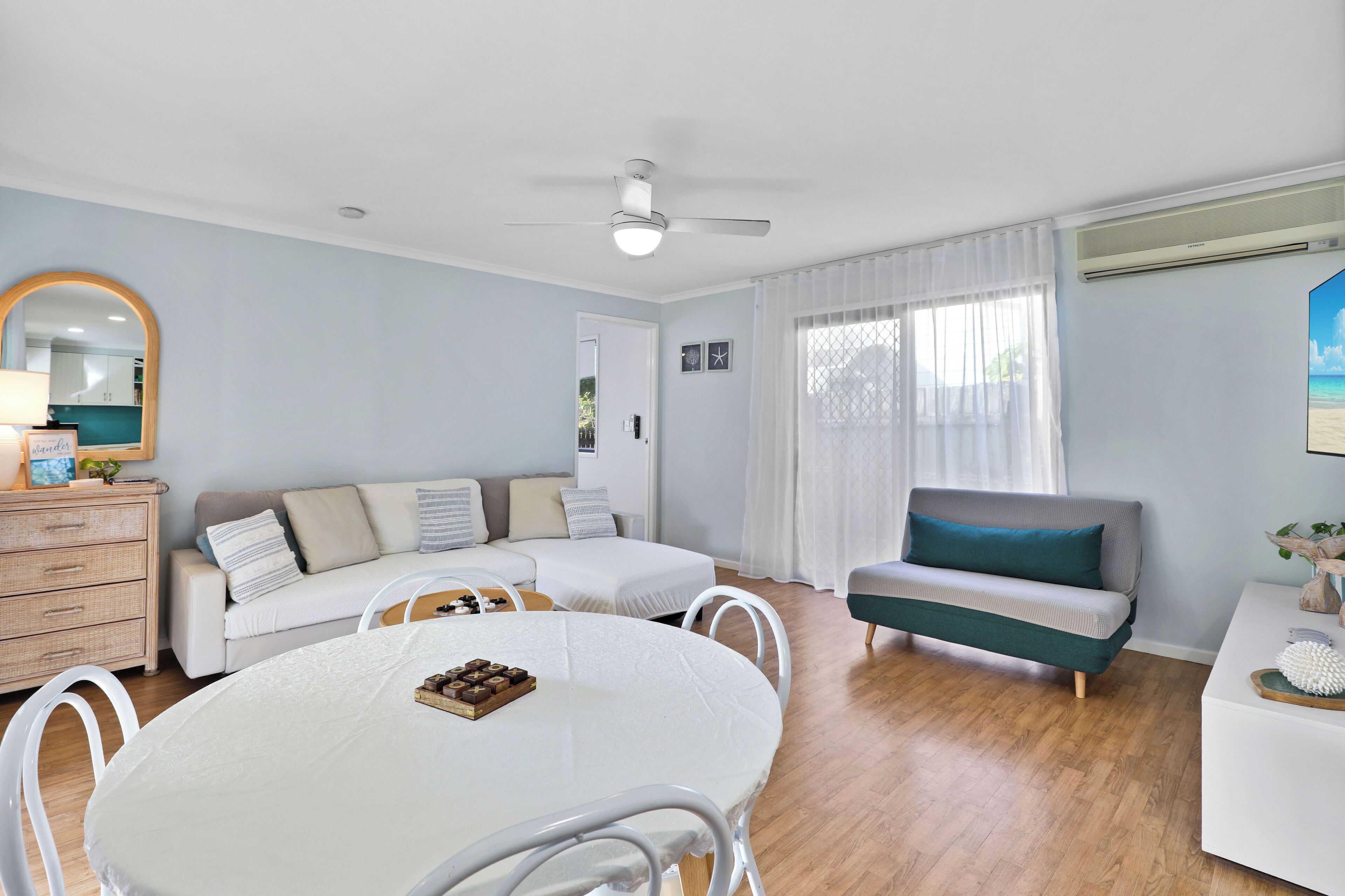 A modern living room with a white round table, a sofa, and a ceiling fan.