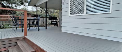 A covered deck with outdoor furniture, a grill, and a house number 27.
