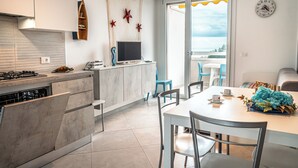 A modern kitchen with a built-in stove, a flat-screen TV, and a dining area with a table and chairs. - Seaside Retreat With Terrace in Bibione (San Michele al Tagliamento)