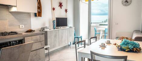 Una cocina moderna con estufa integrada, un televisor de pantalla plana y una zona de comedor con mesa y sillas.