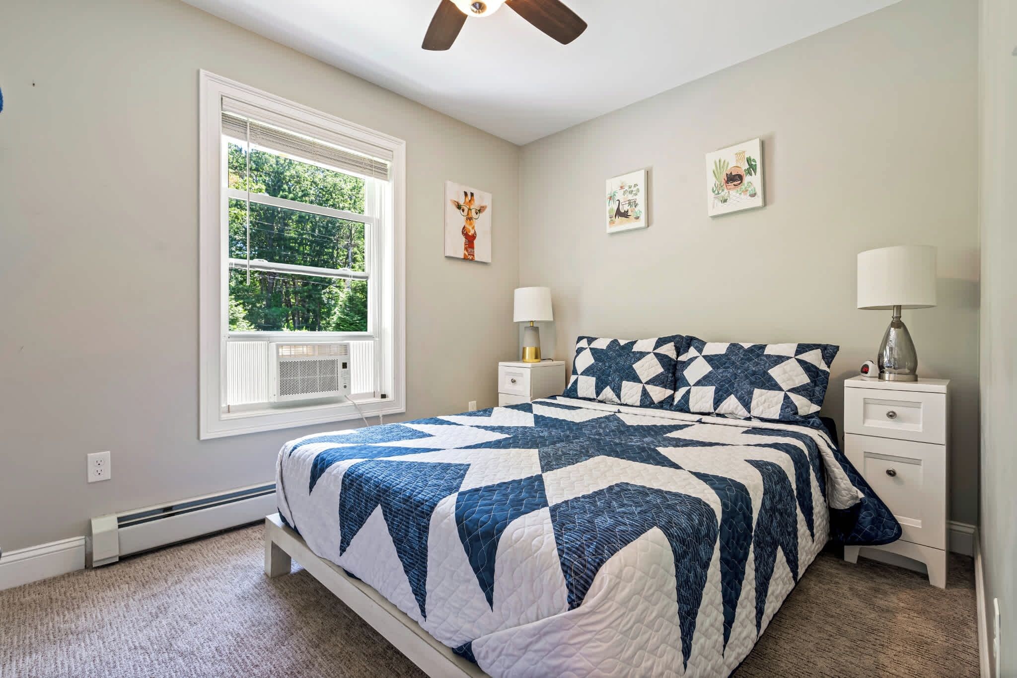 A bedroom with a bed, a window, a ceiling fan, and wall art.