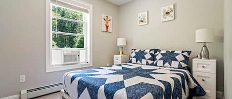 A bedroom with a bed, a window, a ceiling fan, and wall art.