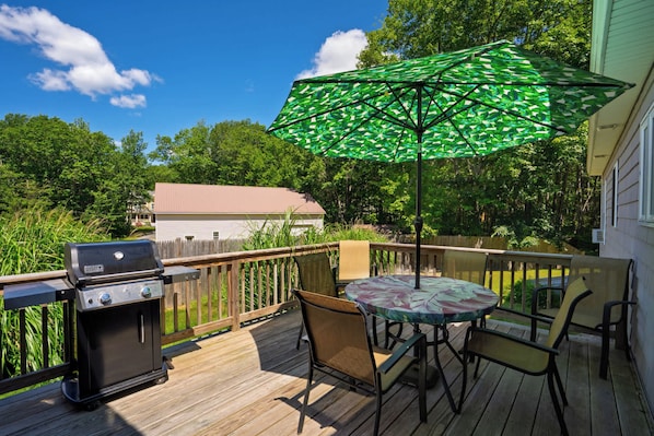 A deck with a grill, outdoor table, chairs, and a green umbrella. - Single Level 4BR Pet-Friendly Home (Kennebunkport)