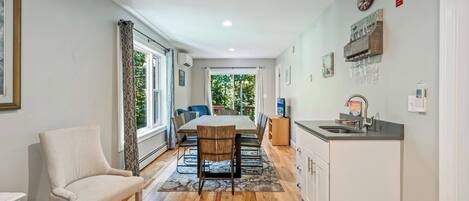 A modern kitchen with a dining area, wooden flooring, and a view to the outdoors.