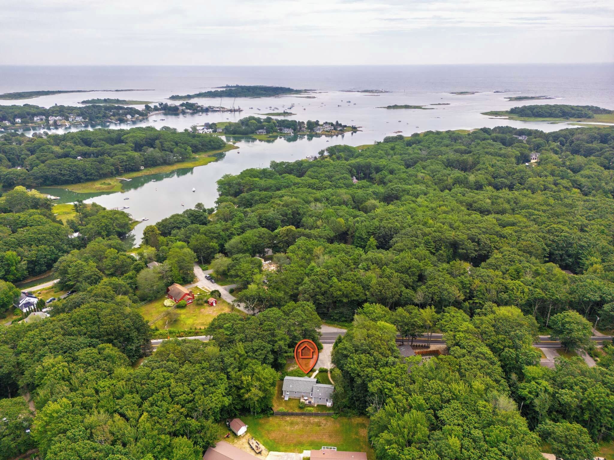 Une vue aérienne d’une zone côtière, caractérisée par une végétation luxuriante, un petit village et une étendue d’eau où se trouvent des bateaux.