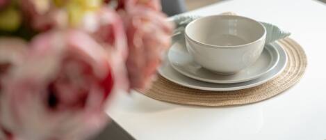 Une table blanche avec un bol et une soucoupe posés sur un set de table en fibres tressées.
