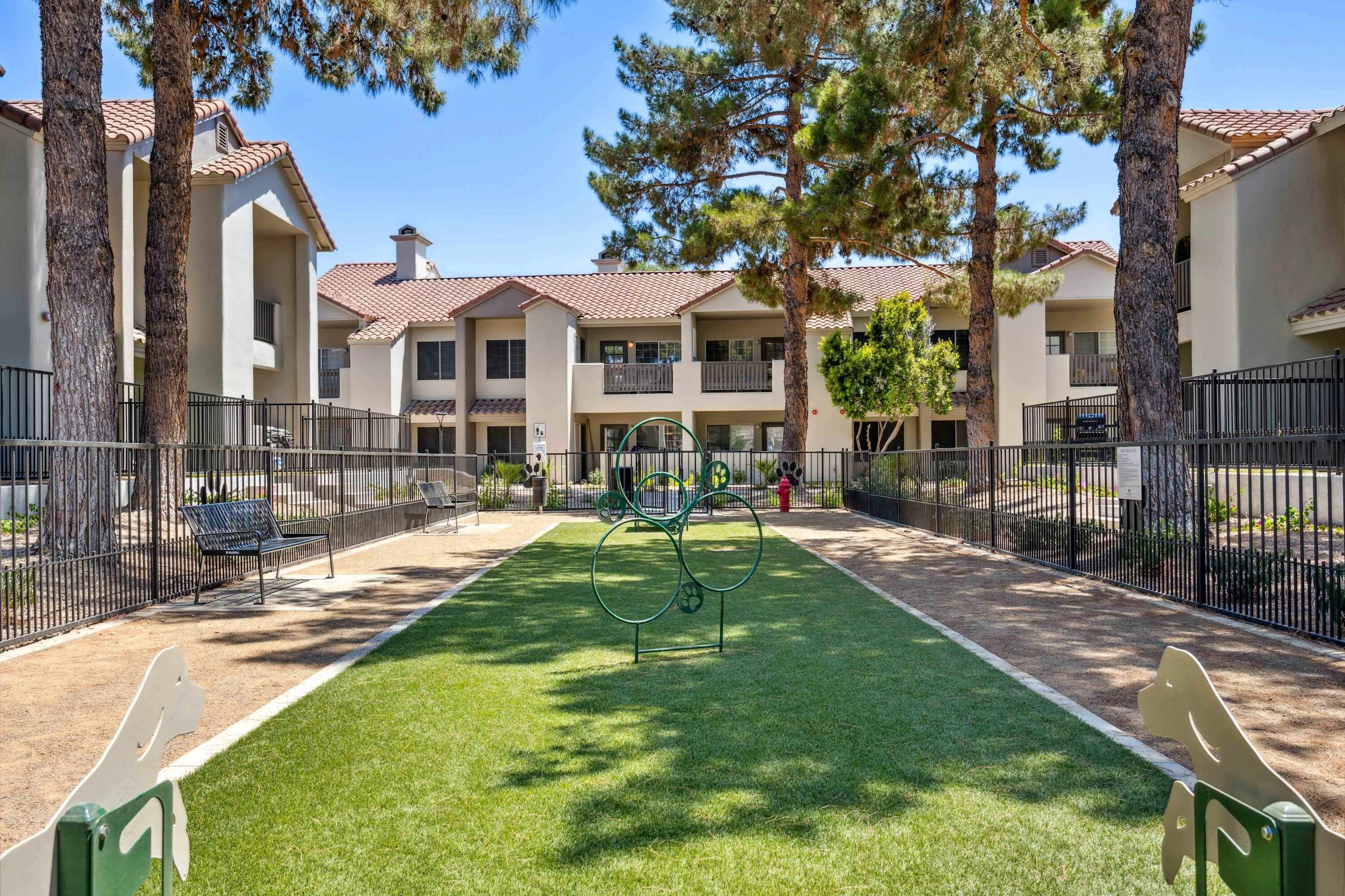 A courtyard with a green lawn, metal benches, and a fire hydrant.
