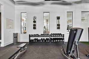 A gym with exercise equipment, including dumbbells and a bench press.