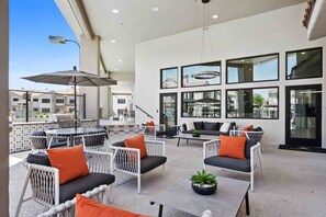 An outdoor patio area with seating arrangements, a grill, and a view of the cityscape.