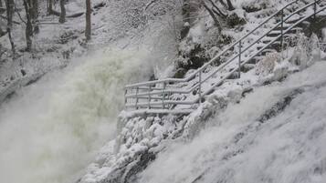 Escena nevada al aire libre con una escalera que desciende por una pendiente cubierta de nieve.