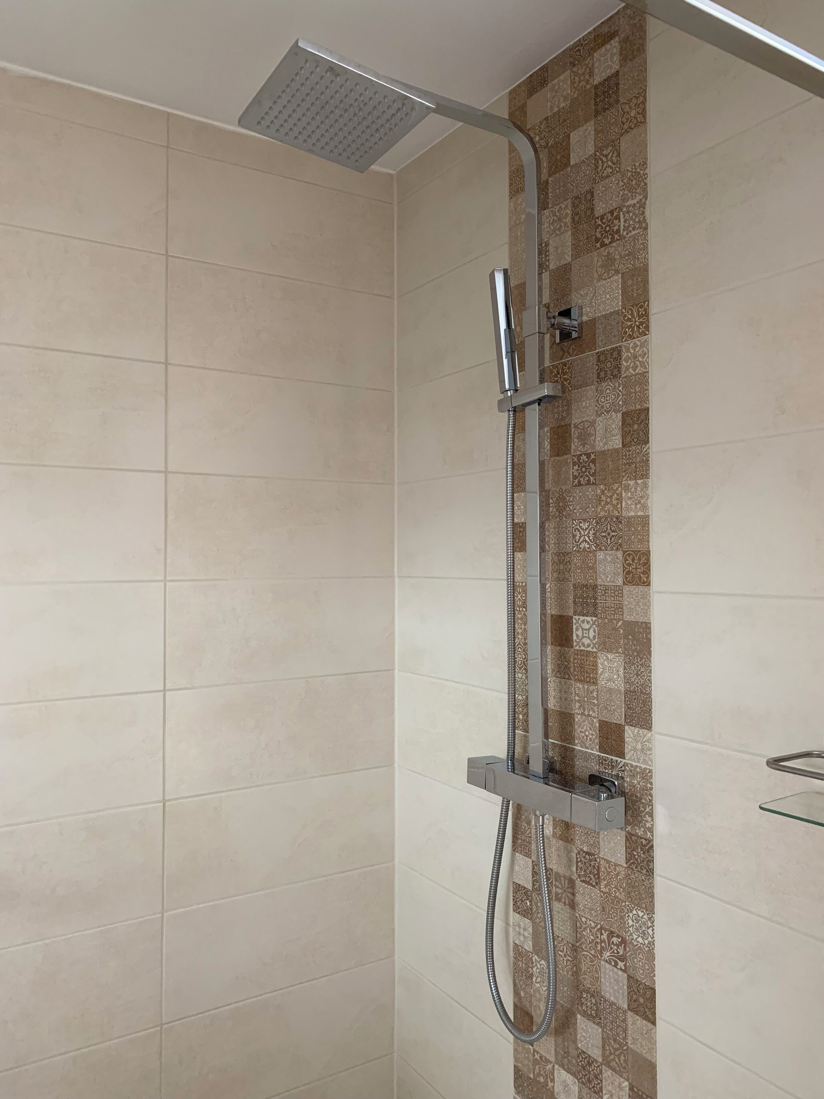 A shower with a modern design, including a square showerhead and a handheld showerhead.