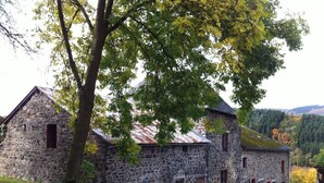 A stone building with a sloped roof, multiple windows, and a door. - Le Baron Suites & Apartments (Stavelot)