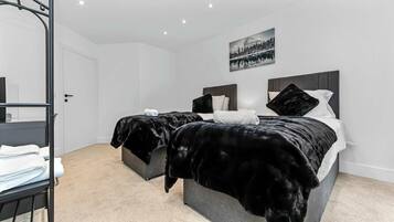A modern bedroom with two beds, a bunk bed, a large window, and a painting on the wall.