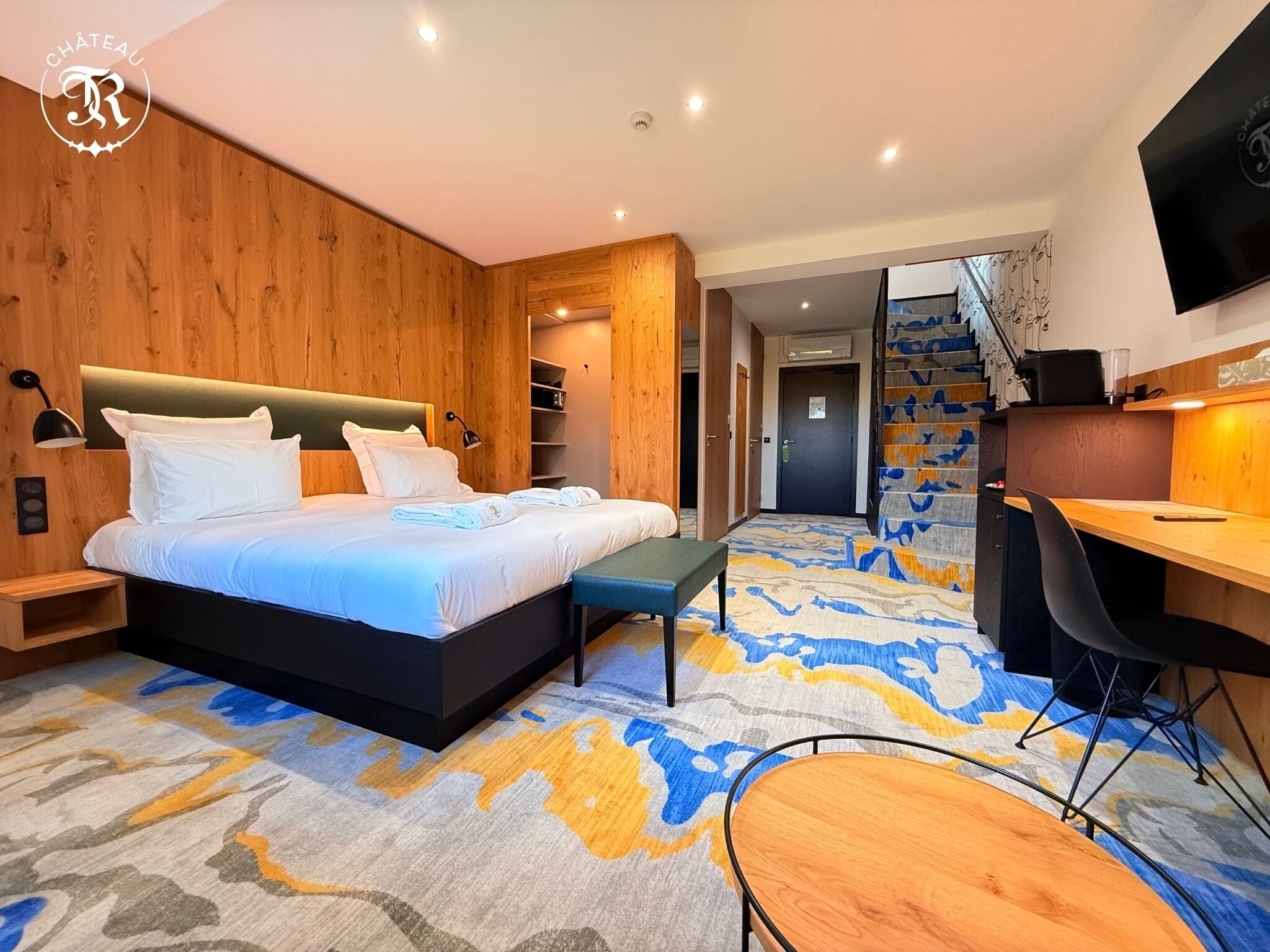 Ein modernes Schlafzimmer mit einem großen Bett, einem Schreibtisch und einer Treppe.