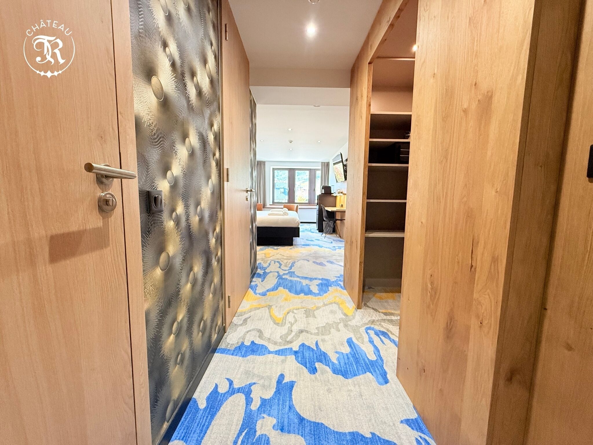 A hotel room with a bed, a desk, and a wardrobe.