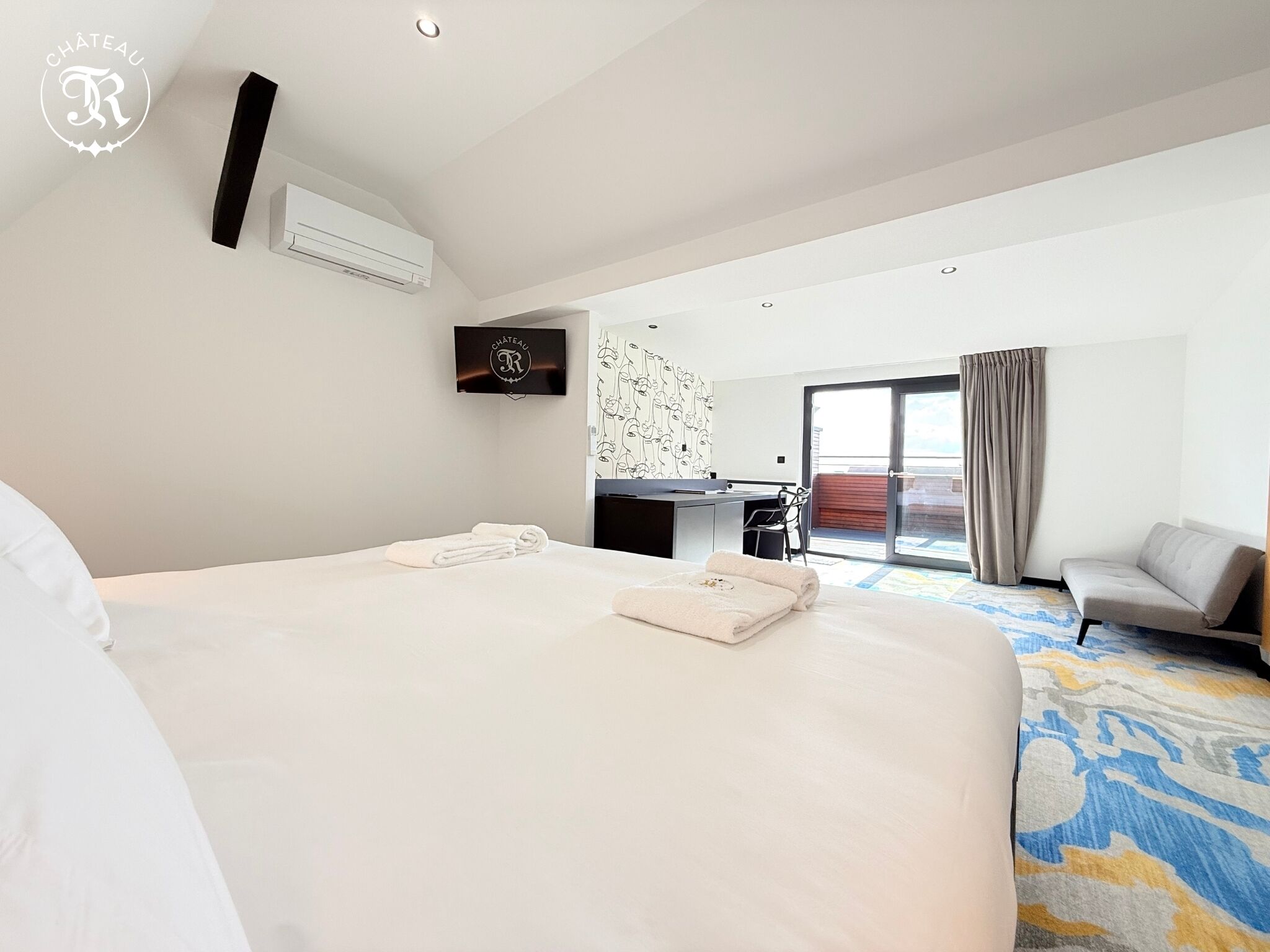 Une chambre d’hôtel avec un grand lit, un bureau, une chaise et une vue sur l’extérieur.