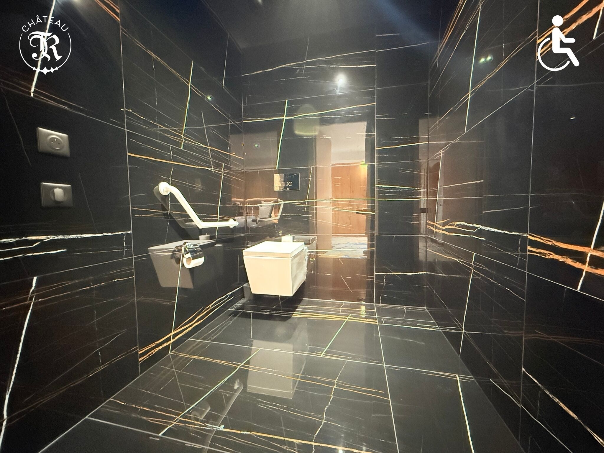 Ein modernes Badezimmer mit schwarzem Marmorboden, einer weißen Toilette und einem Handdesinfektionsmittelspender.