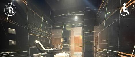 Ein modernes Badezimmer mit schwarzem Marmorboden, einer weißen Toilette und einem Handdesinfektionsmittelspender.