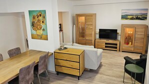 A modern living room with a wooden dining table, sofa, TV, and wooden cabinets. - Central apartment 70 m² up to 4 persons - close to the main station & trade fair Essen (Essen)