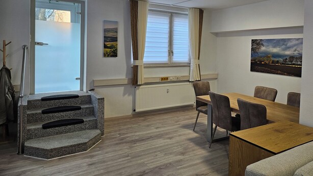 A modern, well-lit room with a dining table, chairs, a staircase, and a window with curtains. - Central apartment 70 m² up to 4 persons - close to the main station & trade fair Essen (Essen)